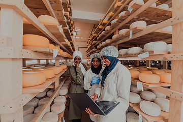 Image showing Arab business partners checking the quality of cheese in the industry and enter data into a laptop. Small business concept