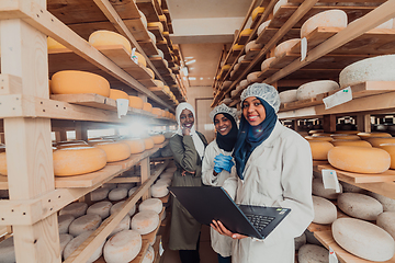 Image showing Arab business partners checking the quality of cheese in the industry and enter data into a laptop. Small business concept