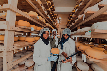 Image showing Arab business partners checking the quality of cheese in the industry and enter data into a laptop. Small business concept