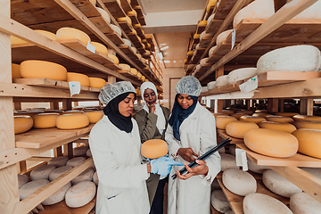 Image showing Arab business partners checking the quality of cheese in the industry and enter data into a laptop. Small business concept