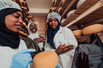 Image showing Arab business partners checking the quality of cheese in the industry and enter data into a laptop. Small business concept