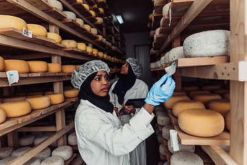 Image showing Arab business partners checking the quality of cheese in the industry and enter data into a laptop. Small business concept