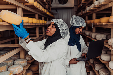 Image showing Business of a Muslim partners in a cheese warehouse, checking the quality of cheese and entering data into laptop