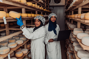 Image showing Business of a Muslim partners in a cheese warehouse, checking the quality of cheese and entering data into laptop