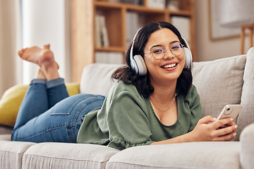 Image showing Woman, portrait and headphones with smartphone on sofa, for hearing radio, online subscription and podcast. Happy female person listening to music, streaming audio and sound on mobile in living room