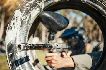 Image showing Paintball, shooting and target with man in playground for battlefield, mission and soldier. Sports, games and action with person and gun in tire in arena for challenge, adventure and warrior training