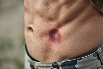 Image showing Paintball injury, stomach bruise and man in closeup with pain, shooting or accident for outdoor war games. Abdomen, emergency and wound in military training, zoom and battlefield for exercise in army