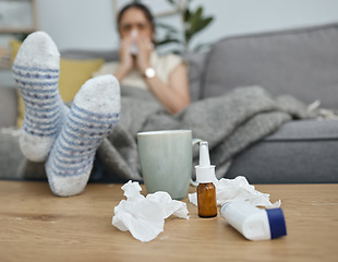 Image showing Medicine, table and sick woman in home, sofa or living room with paper, blowing nose or pain from virus. Girl, asthma inhaler and medical problem with water, tissue and feet on a desk in house