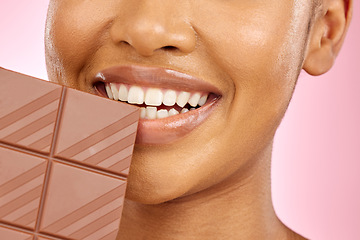 Image showing Woman, mouth and chocolate in studio closeup with smile, eating and skin glow for beauty by pink background. Girl, model and diet with sweets, snack or candy for cheat day, cosmetics and headshot