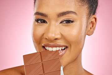 Image showing Woman, chocolate and bite in studio portrait with smile, eating and skin glow for beauty by pink background. Girl, model and diet with sweets, snack or candy for cheat day, cosmetics and headshot