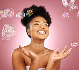 Image showing Beauty, bubbles and a happy woman with skin care in studio for wellness and dermatology glow. Happy, natural makeup and face cosmetics of a black female model with facial shine on a pink background