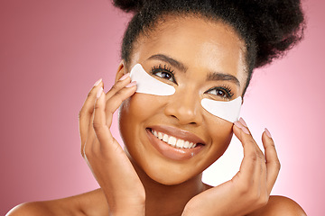 Image showing Skincare, face and black woman with pad on eyes, cosmetics and dermatology on pink background. Beauty, collagen product and happy model eye patches for healthy skin glow, smile and care in studio.