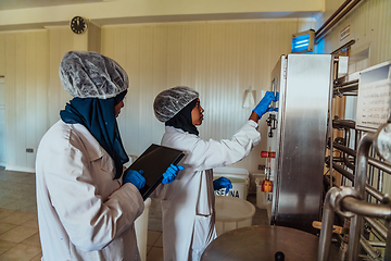 Image showing Arab business partners checking the quality of cheese in the industry and enter data into a laptop. Small business concept