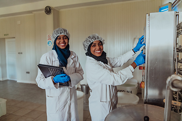 Image showing Arab business partners checking the quality of cheese in the industry and enter data into a laptop. Small business concept