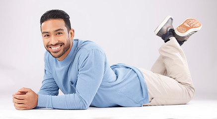 Image showing Fashion, portrait and happy man on the floor in studio isolated on a white background. Style, smile and Asian person from Cambodia in casual clothes, trendy aesthetic or confidence to relax on ground