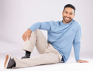 Image showing Portrait, fashion and happy man on the floor in studio isolated on a white background. Style, smile and Asian person from Cambodia in casual clothes, trendy aesthetic or confidence to relax on ground