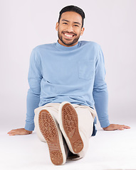 Image showing Portrait, fashion and man smile on the floor in studio isolated on a white background. Style, happy and Asian person from Cambodia in casual clothes, trendy aesthetic or confidence to relax on ground