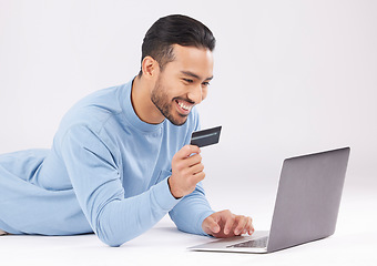 Image showing Man, studio and laptop with credit card, e commerce or payment information with smile by white background. Young asian guy, floor and happy with fintech, sale or deal with virtual customer experience