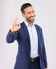 Image showing Wink, portrait and asian man with perfect hand sign for support, agreement or feedback, thank you or review on grey background. Smile, face and emoji okay gesture by male with approval, like or yes