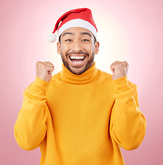 Image showing Portrait, excited and smile, man with Christmas hat for fun and yes at festive holiday on pink background. Happy, winning celebration and model with santa cap and winter vacation success in studio.