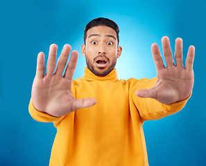 Image showing Stop, hands and portrait of asian man in studio with warning, danger and wait sign on blue background. Face, palm and Japanese male model with caution, fear of surprise, drama or block conflict