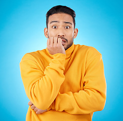 Image showing Anxiety, portrait and asian man biting nails in studio with stress, suspense or crisis on blue background. Face, worry and nervous male with emoji reaction to news, gossip or did you know drama