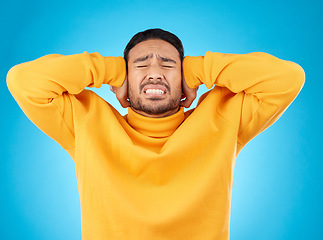 Image showing Stress, headache and hands on ears of man in studio with noise, complaint or crisis on blue background. Anxiety, migraine and frustrated male with vertigo, brain fog or tinnitus, depression or trauma