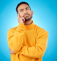 Image showing Thinking, idea and young man in a studio with doubt, confused or choice facial expression. Problem solving, dream and Indian male model brainstorming, question or planning isolated by blue background