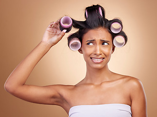 Image showing Hair care, problem and a woman with rollers on a studio background for fail of curls. Sad, beauty and a young Indian model or girl with gear for a curly hairstyle mistake isolated on a backdrop