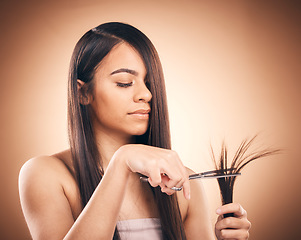 Image showing Woman, hair care and scissors in studio to cut split ends for a healthy shine and growth. Young female aesthetic model on a brown background for self care, cosmetics and beauty with salon tools