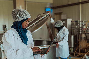 Image showing Arab business partners checking the quality of cheese in the industry and enter data into a laptop. Small business concept