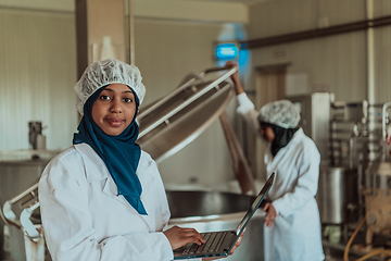 Image showing Arab business partners checking the quality of cheese in the industry and enter data into a laptop. Small business concept