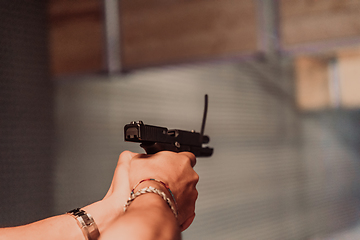 Image showing A man practices shooting a pistol in a shooting range while wearing protective headphones