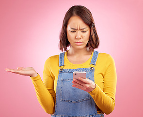 Image showing Reading, studio or Asian woman with cellphone problem, bad news and stress over mistake, crisis or social media. Spam notification, doubt or person confused over smartphone scam on pink background