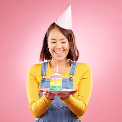 Image showing Birthday cake candle, studio and happy Asian woman excited, smile and celebrate party, present or gift. Congratulations, wow and Japanese person with dessert, candy or sweets on pink background