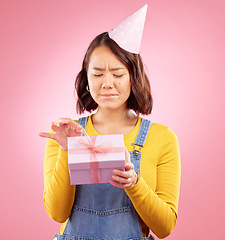 Image showing Birthday present, studio box and Asian woman stress over package, ribbon opening fail or party event. Problem, bad gift mistake and Japanese person with doubt, unsure or sad on pink background