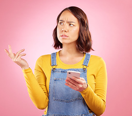 Image showing Confused, studio and Asian woman with smartphone problem, 404 fail and stress over mistake, error or ideas. Thinking, doubt and Japanese person frustrated over online phone glitch on pink background