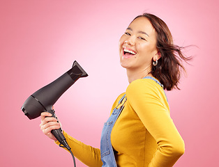 Image showing Wind, salon and hair care with woman and hairdryer in studio for hairdresser, beauty and cosmetics. Shampoo, smile and hairstyle with portrait of asian person on pink background for product and spa