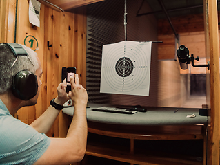 Image showing A man in a shooting range takes a picture and examines the results after shooting