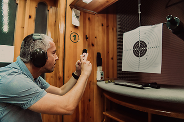 Image showing A man in a shooting range takes a picture and examines the results after shooting