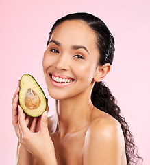 Image showing Beauty, avocado and face of a happy woman with skin care, dermatology and natural glow. Portrait of female aesthetic model with fruit for moisturizer, cosmetics or diet nutrition on a pink background