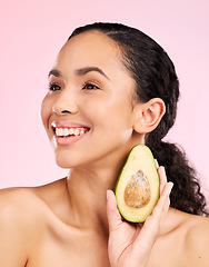 Image showing Avocado, skincare and happy woman thinking of healthy facial, natural cosmetics and beauty ideas. Young african person or model green fruit for vegan product and dermatology on pink studio background