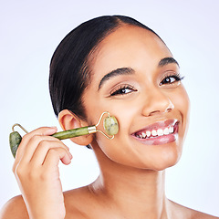 Image showing Facial roller, natural beauty and woman massage skin for wellness and glow. Portrait of a young aesthetic female model happy with dermatology, self care and face tools results on a studio background