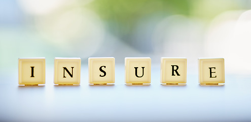 Image showing Letters, blocks and an insurance message on a desk for business, security or finance with bokeh. banner, mockup and a word on a table at a financial company for profit, investment or savings