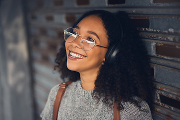 Image showing .Thinking, music and smile with a woman in the city, streaming or listening to the radio using headphones. Face, idea and audio with a happy young female person hearing sound in an urban town.