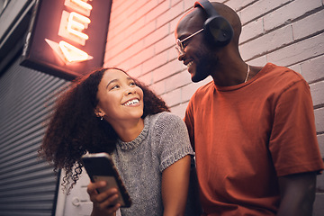 Image showing Phone, music and headphones with an interracial couple outdoor in a city together for dating. Love, mobile app or streaming with a man and woman bonding in an urban town while listening to the radio