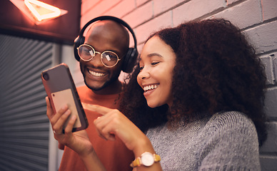 Image showing Phone, music and headphones with a multicultural couple outdoor in a city together for dating. Love, mobile or streaming app with a man and woman bonding in an urban town while listening to the radio