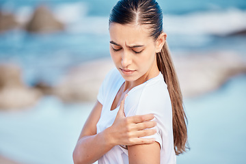 Image showing Woman, fitness and arm pain on beach from workout injury, exercise or outdoor accident. Female person with sore shoulder, joint ache or inflammation and muscle tension after exercise on ocean coast