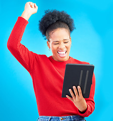 Image showing Happy woman, tablet and fist pump for winning, discount or sale against a blue studio background. Excited female person in celebration with technology for good news, bonus promotion or lottery prize