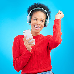 Image showing Happy woman, headphones and listening to music for audio streaming against a blue studio background. Excited female person dancing and enjoying sound track or entertainment with mobile smartphone